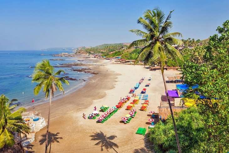 "Tourists enjoying water sports and basking on the beach in Goa, India."