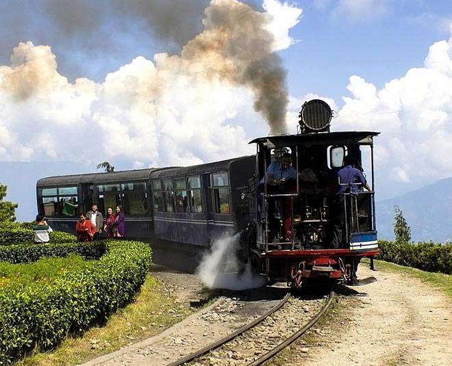 Tourists enjoying a scenic train ride through the picturesque landscapes of Darjeeling, surrounded by lush greenery and majestic mountains - an unforgettable travel experience."