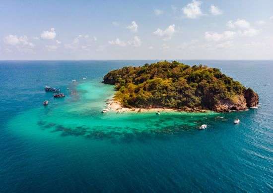 "A panoramic view of an island in the Andaman and Nicobar archipelago, with lush green forests and blue waters surrounding it."