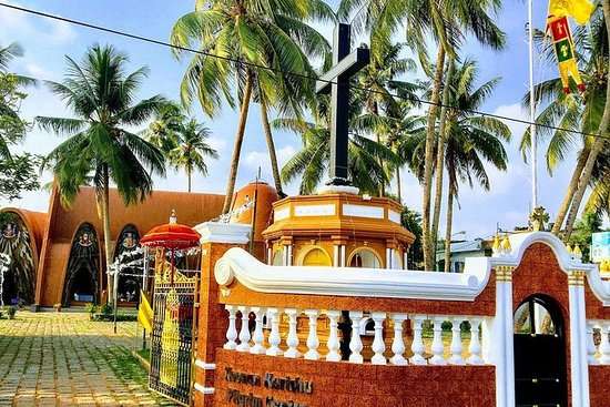 "Exterior view of South Indian resort in a beautiful dark orange color, surrounded by lush greenery and overlooking a serene lake."