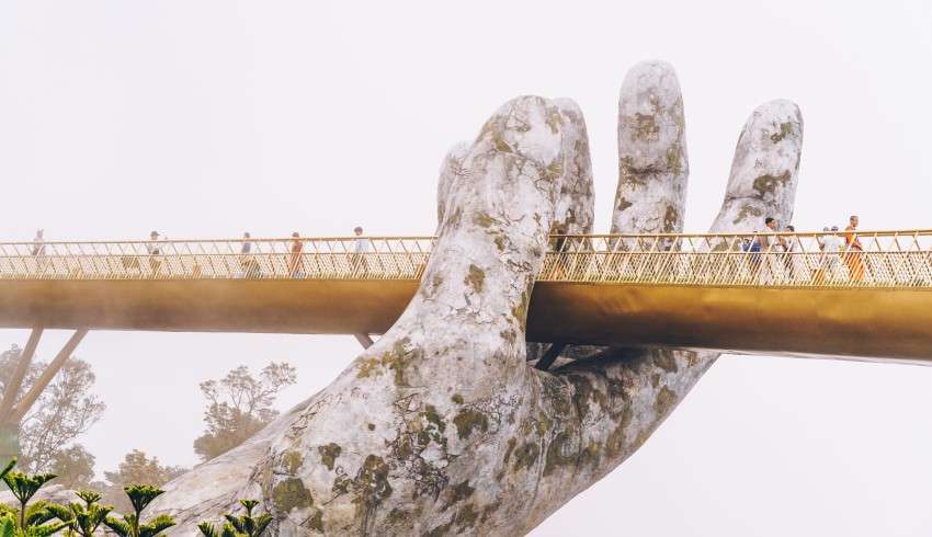 "Golden Bridge held up by giant stone hands" could be a possible alt text for an image of the Golden Bridge in Vietnam.