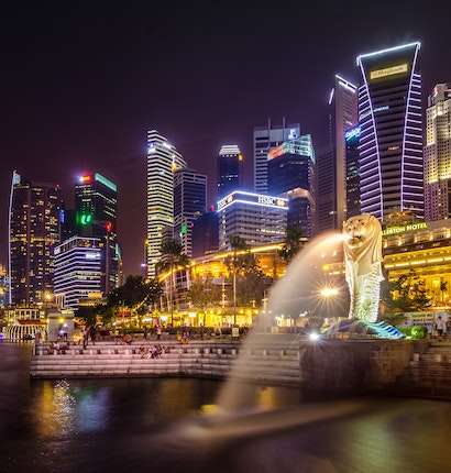 Merlion statue in Singapore illuminated with colorful lights in the night