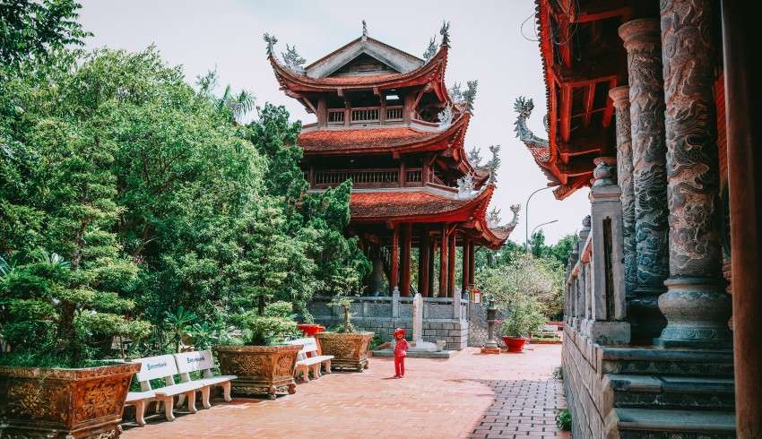 "Trúc Lâm Phương Nam Zen Monastery in Vietnam with trees, lake, and mountains in the background"