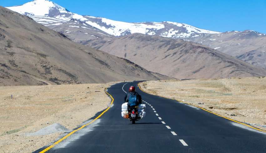 "Shanti Stupa, Ladakh surrounded by snow-capped mountains and covered in snow."