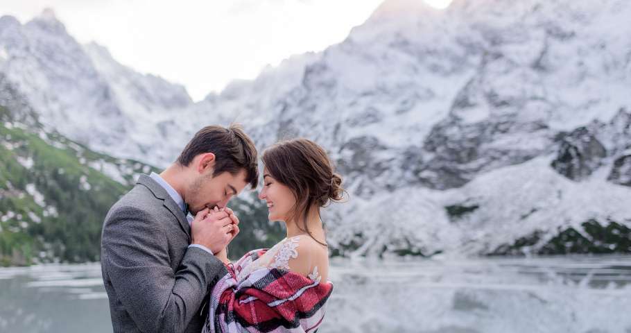 Honeymoon in Switzerland and Netherland in Winter wedding couple embracing by the frozen lake in the mountains.